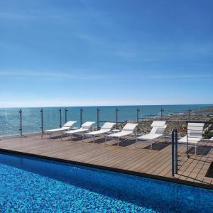 una piscina con sedie e l'oceano sullo sfondo di Hotel Atlantico a Lido di Jesolo