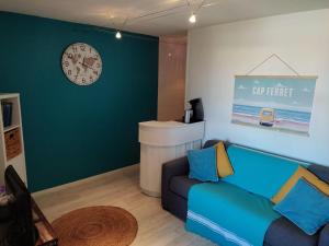 a living room with a couch and a clock on the wall at appartement T2 biscarosse plage in Biscarrosse-Plage