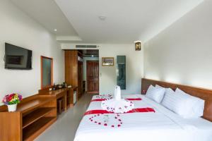 1 dormitorio con 1 cama blanca grande con detalles en rojo en Baan Vanida Garden Resort, en Karon Beach