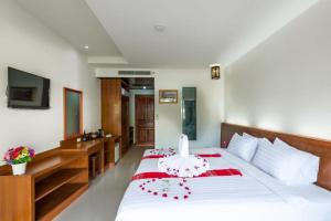 a bedroom with a large white bed with red accents at Baan Vanida Garden Resort in Karon Beach