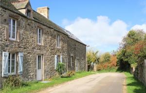 an old stone house with a road next to it at La Petite Mainnerie in Omonville-la-Petite