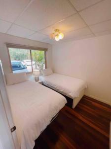 two beds in a small room with a window at Oasis on the Hawkesbury - Water Views in Brooklyn