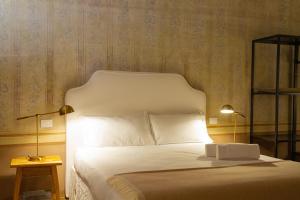 una camera da letto con un grande letto bianco con due lampade di Palazzo Glori 6 a Cremona