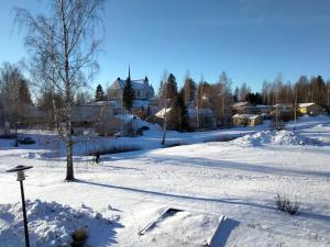 un campo cubierto de nieve con una ciudad al fondo en Kuhmoisten Kivilinna, en Kuhmoinen