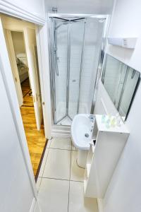 a white bathroom with a shower and a sink at The Dubliner Central - O Connell Street Zone in Dublin
