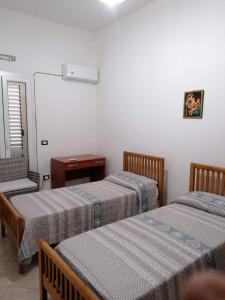Zimmer mit 2 Betten, einem Tisch und einem Spiegel in der Unterkunft LOCAZIONE TURISTICA " Su Passizzeri " in Suni