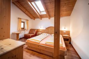 a bedroom with a bed and a chair in a room at Hof Zerund in Castelrotto