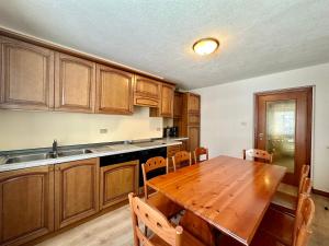 a kitchen with a wooden table and wooden cabinets at Central Apartment Canazei in Canazei