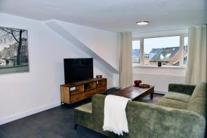 een woonkamer met een bank en een tv bij Villa Aix in Kerkrade