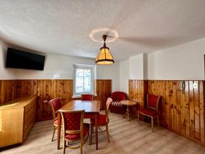 comedor con mesa, sillas y TV en Central Apartment Canazei en Canazei