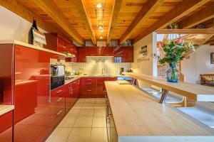 een grote keuken met rode kasten en een houten tafel bij Kercolo - Maison de campagne à 10min des plages in Surzur