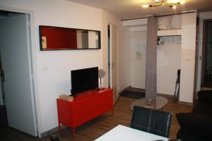 a living room with a tv and a red cabinet at Villa Blanche appartement 2 in Le Mont-Dore