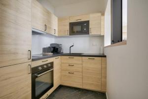 La cuisine est équipée d'armoires en bois et d'un four noir. dans l'établissement Bel appartement avec lit double dans Paris 15ème, à Paris