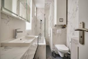La salle de bains blanche est pourvue d'un lavabo et de toilettes. dans l'établissement Bel appartement avec lit double dans Paris 15ème, à Paris