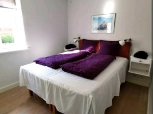 a bedroom with a bed with purple pillows on it at Birkevang holiday apartment in idyllic countryside in Faxe