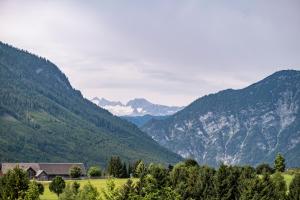 a house in a valley with mountains in the background at Narzissen Vital Resort Bad Aussee in Bad Aussee