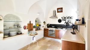 a kitchen with white walls and wooden cabinets at Casa Litali by Rentbeat in Ostuni
