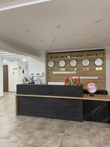 un vestíbulo de hotel con relojes en la pared y un mostrador en Ulug`bek Grand Hotel en Samarcanda