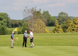 a group of three men standing on a golf course at Wigley Orchard in Clifton upon Teme