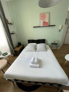 ein Schlafzimmer mit einem weißen Bett und zwei Hausschuhen darauf in der Unterkunft Le studio 37 - Cœur de Rennes - Proche gare in Rennes