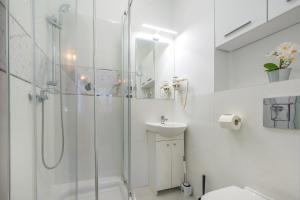 a white bathroom with a shower and a sink at Hello Apartments Modern Studio Sw Ducha in Gdańsk
