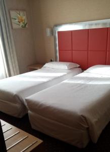 2 letti in camera con testiera rossa di Hotel Susa a Milano