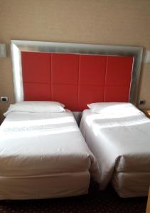 two beds in a hotel room with a red headboard at Hotel Susa in Milan