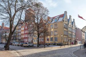 a cobblestone street in a city with buildings and cars at Hello Apartments Modern Studio Sw Ducha in Gdańsk
