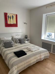 ein großes Bett in einem weißen Schlafzimmer mit einem Fenster in der Unterkunft Apt 2 chambres au coeur de Uccle in Brüssel