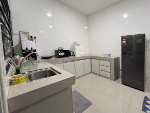 a kitchen with a sink and a black refrigerator at 53 Mountainville Semi-D Bungalow-13-18pax in Ipoh
