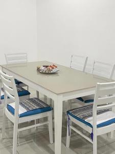 une table blanche avec quatre chaises et une plaque de cuisson dans l'établissement 53 Mountainville Semi-D Bungalow-13-18pax, à Ipoh