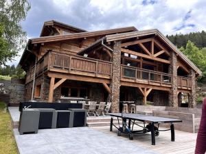 une grande maison en bois avec une table devant dans l'établissement Le Paradis de Marie, à Gérardmer