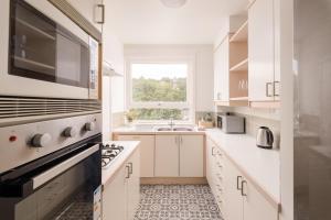 a white kitchen with a sink and a window at The Canongate Apartment in Edinburgh