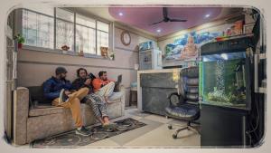 three people sitting on a couch in a room with an aquarium at Shri Ganga View Guest House in Rishīkesh