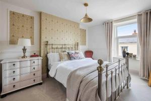 a bedroom with a bed and a dresser and a window at Pittman Cottage in Torquay