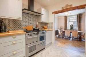 a kitchen with a stove and a dining room at Pittman Cottage in Torquay