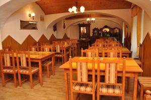 un comedor lleno de mesas y sillas de madera en Gloriett Panzió, en Fertőboz