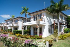 a large white house with palm trees and flowers at Bahia Del Sol Villas & Condominiums in San Juan del Sur