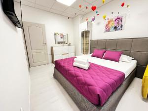 Tevi Apartments في مدينة فارنا: غرفة نوم بسرير كبير مع بطانية ارجوانية