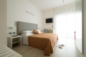 a white bedroom with a bed and a window at Hotel Pillon in Bibione