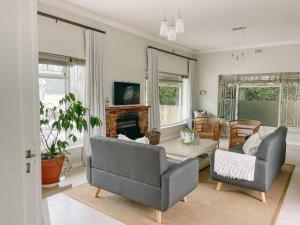 a living room with two chairs and a fireplace at Leisure Isle Seaside Cottage in Knysna