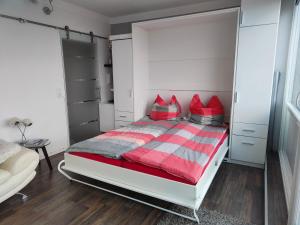 a bedroom with a red and gray bed with red pillows at Ferienwohnung-Kassiopeia in Laboe