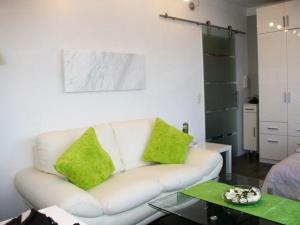 a living room with a white couch with lime green pillows at Ferienwohnung-Kassiopeia in Laboe