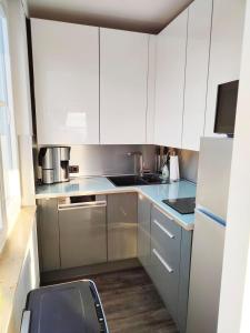 a kitchen with white cabinets and stainless steel appliances at Ferienwohnung-Kassiopeia in Laboe