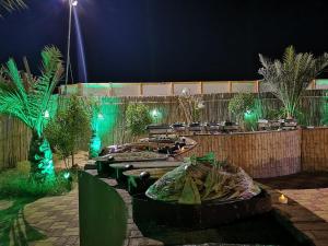 a garden at night with benches and green lights at Dream Night Tourism LLC in Hunaywah