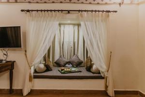 Cama en habitación con ventana y cortinas en Gir Lion Safari Camp by Trulyy, Sasan Gir, en Sodaori