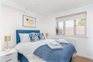 a bedroom with a blue and white bed and a window at Castle Townhouse Kenilworth - Private Parking - 24 Hr Gym Access - Town Centre in Kenilworth