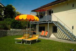 une table et des chaises avec un parasol dans l'herbe dans l'établissement Ferien im Hummelhaus, à Lindau