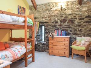 a bedroom with bunk beds and a stone wall at Swallow Lodge in Mathry