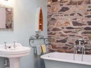 a bathroom with a sink and a stone wall at Swallow Lodge in Mathry